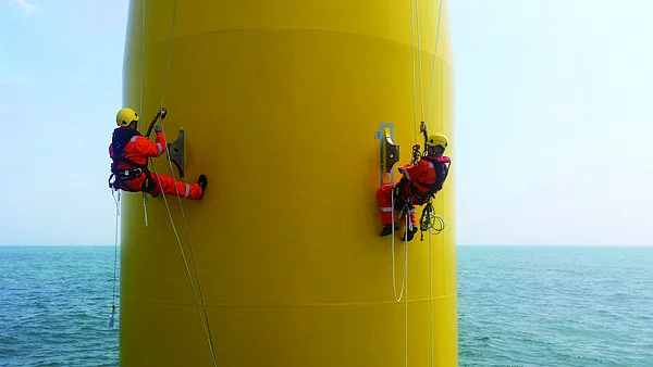 Rope-access technicians working on an offshore wind turbine foundation