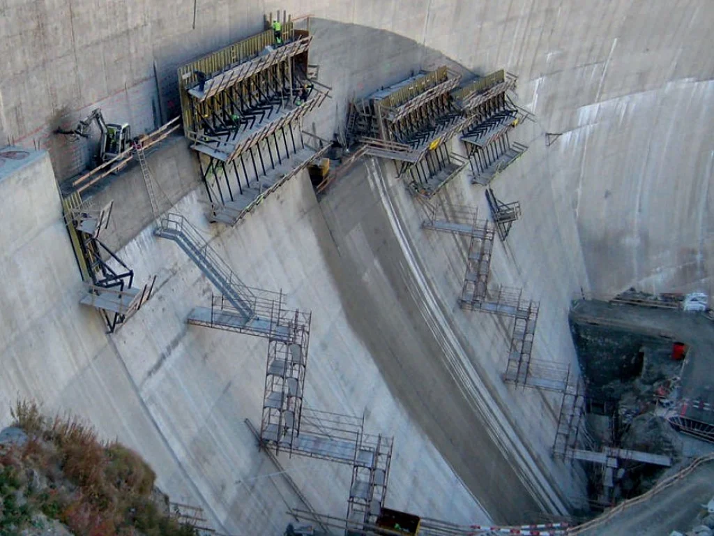 Aerial view of a concrete dam under construction with wall formwork and stair-tower access